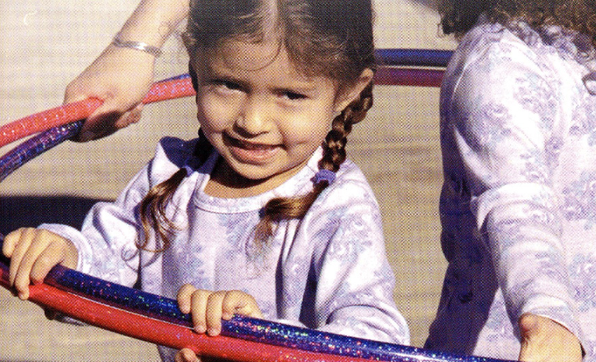 Little girl playing with hula hoop.