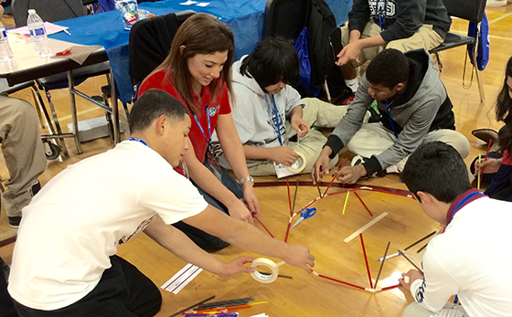 Oralia providing hands-on support in building a geodesic dome with a some youth interested in pursuing STEM education.