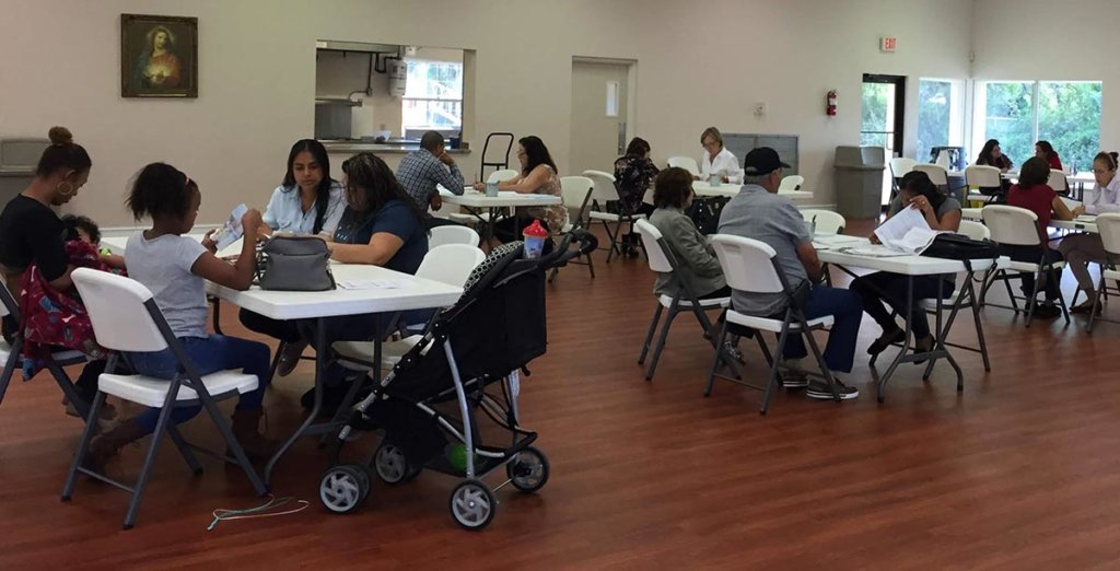 RCMA staff and volunteers prepare citizenship applications and fee waivers for community members at a local church. | New Americans