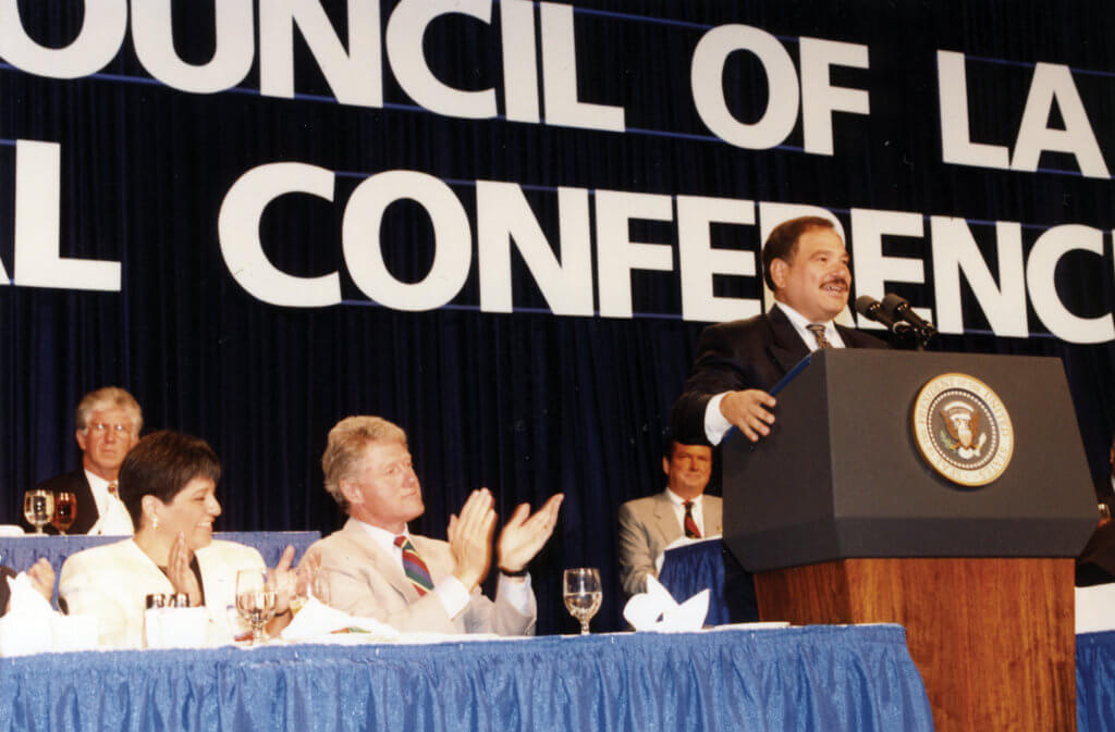 Raul Yzaguirre addresses attendees at an NCLR Annual Conference alongside President Bill Clinton.