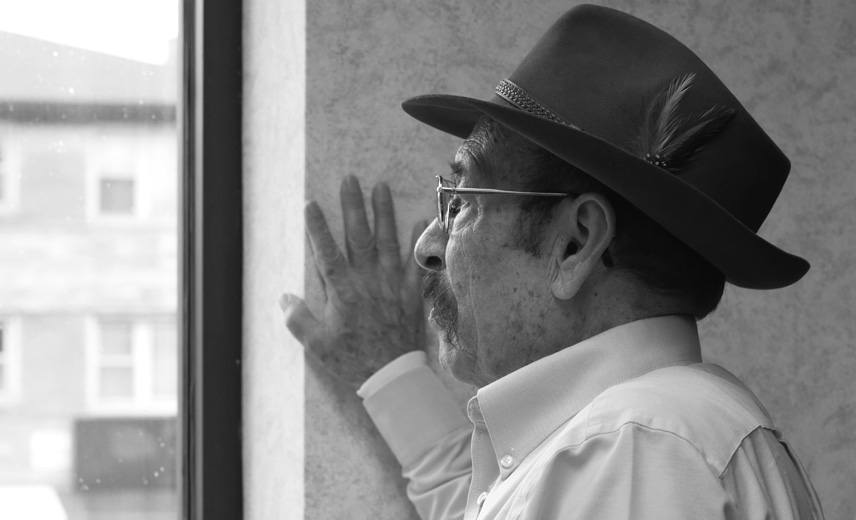Elderly gentleman looking out of a window.