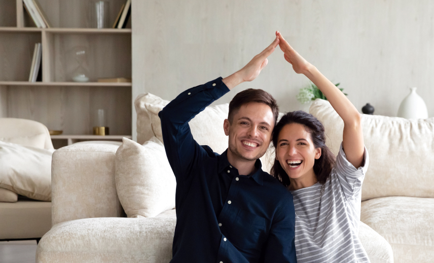Young couple in their new home making a roof with your joined hands above their heads.