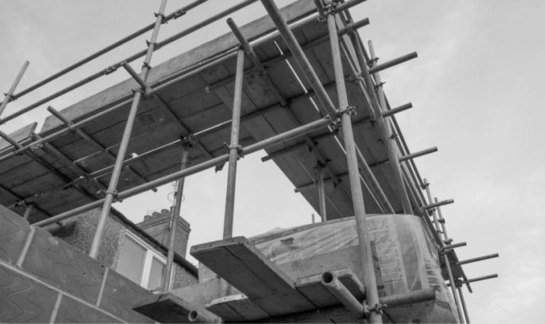 A black and white photograph of scaffolding for a construction project against a clear sky.