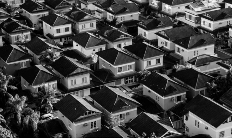 A black and white photograph of rows of tightly packed two-story homes.
