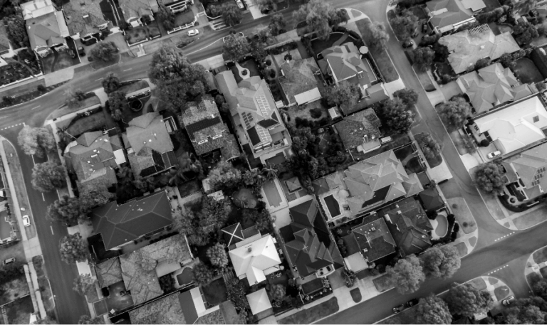 A black and white aerial photograph of houses in a suburban area.