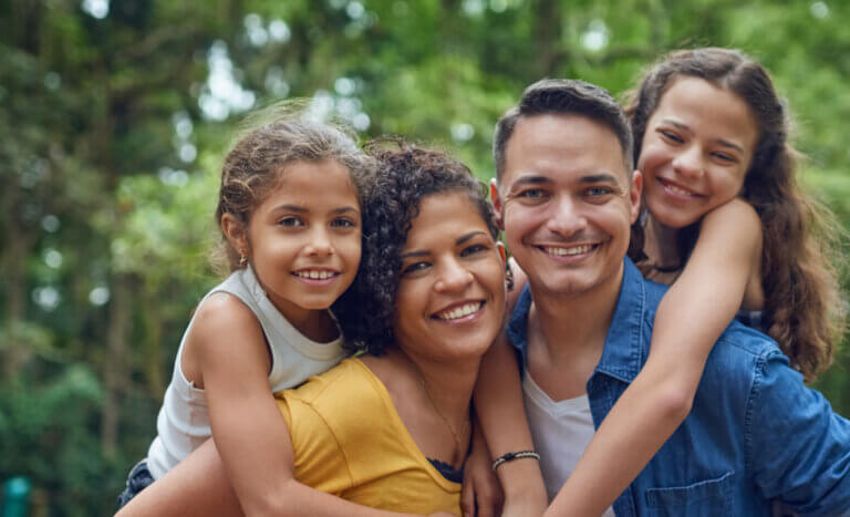 Latino family of four in a park looking at the camera.