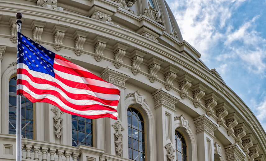 Close-up of the U.S. Capitol Dome with the American flag waving in the foreground.