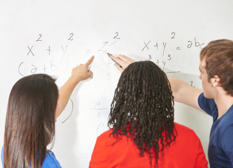 Teenagers solving a math problem on a white board