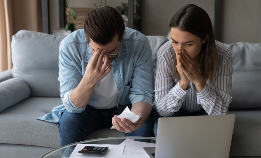 Upset Latino millennial married couple sit on couch reading financial papers invoices troubled with too high expenses utility costs.